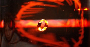 A woman looks at the original ring from the film "The Lord of the Rings" January 30, 2007 at an exhibition in Potsdam, eastern Germany. (MICHAEL URBAN/DDP/AFP via Getty Images)