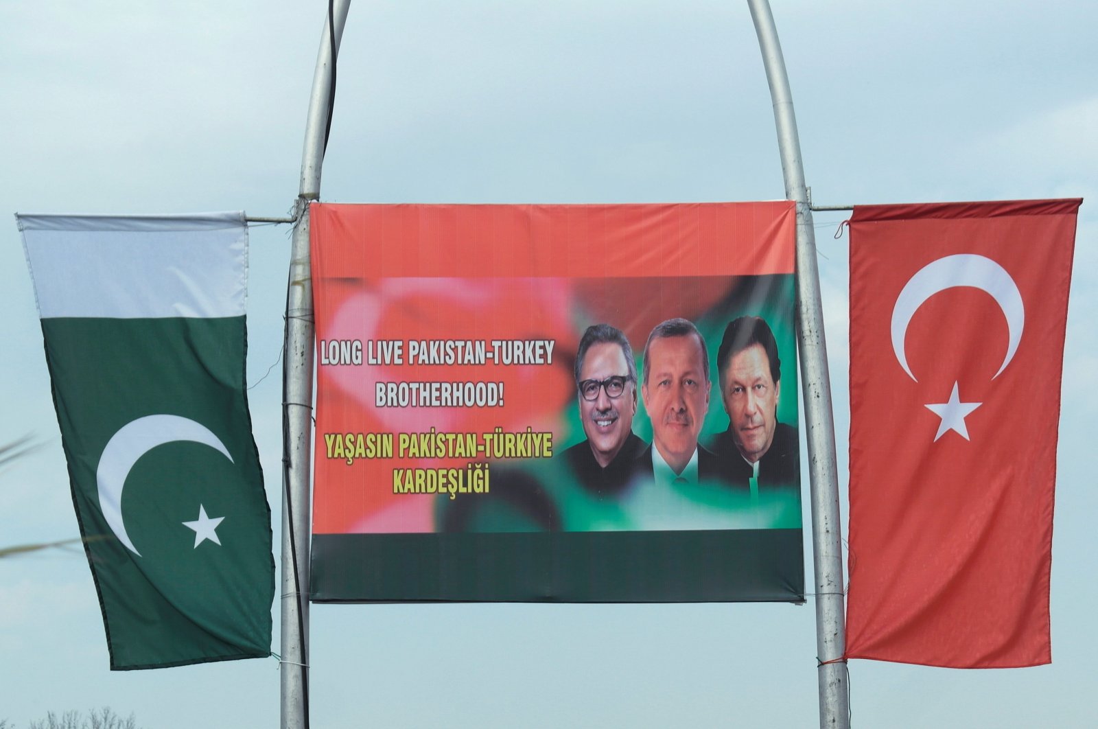 The Pakistani (L) and Turkish national flags hang from either side of a sign showing Pakistan's President Arif Alvi (L), President Tayyip Erdoğan (C) and Pakistan's Prime Minister Imran Khan, in Islamabad, Pakistan, Feb. 13, 2020. (Reuters Photo)
