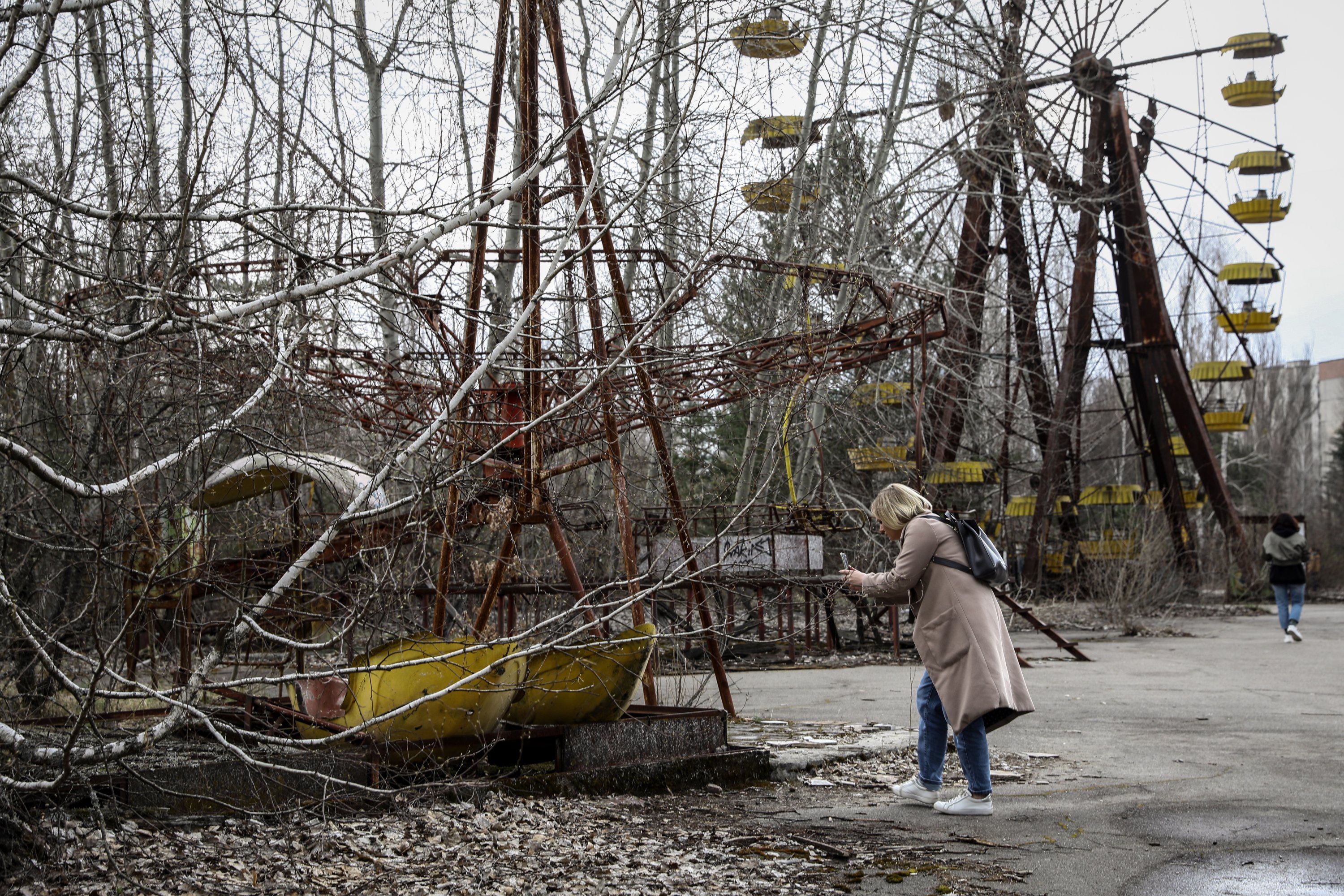 A woman photographs an old carousel near the Ferris wheel in the abandoned city of Pripyat, near Chernobyl, Ukraine, April 15, 2021. (EPA Photo)