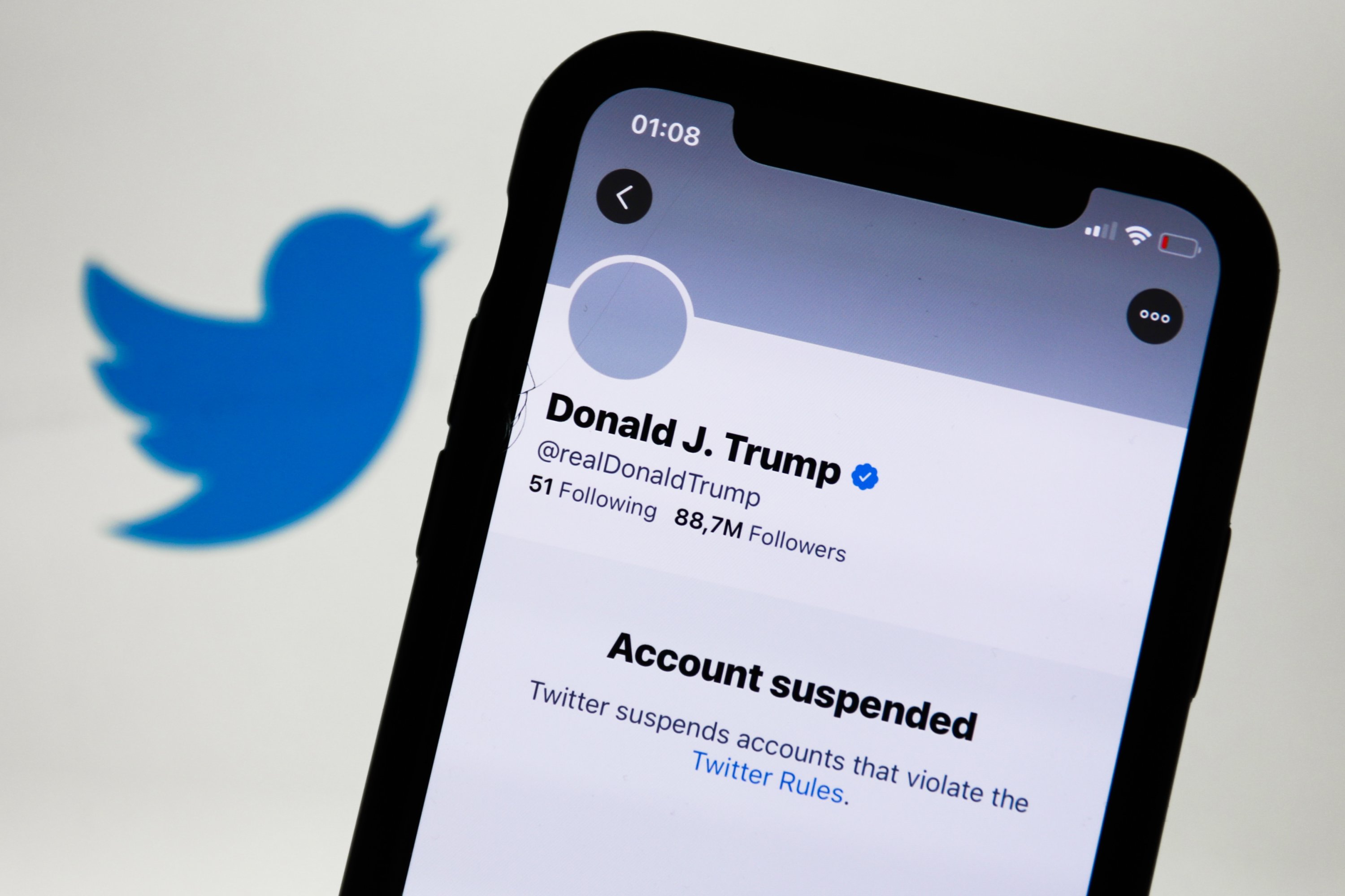 Then U.S. President Donald Trump's suspended Twitter account is displayed on a phone screen with the Twitter logo in the background, Poland, Jan. 9, 2021. (Photo by Getty Images)
