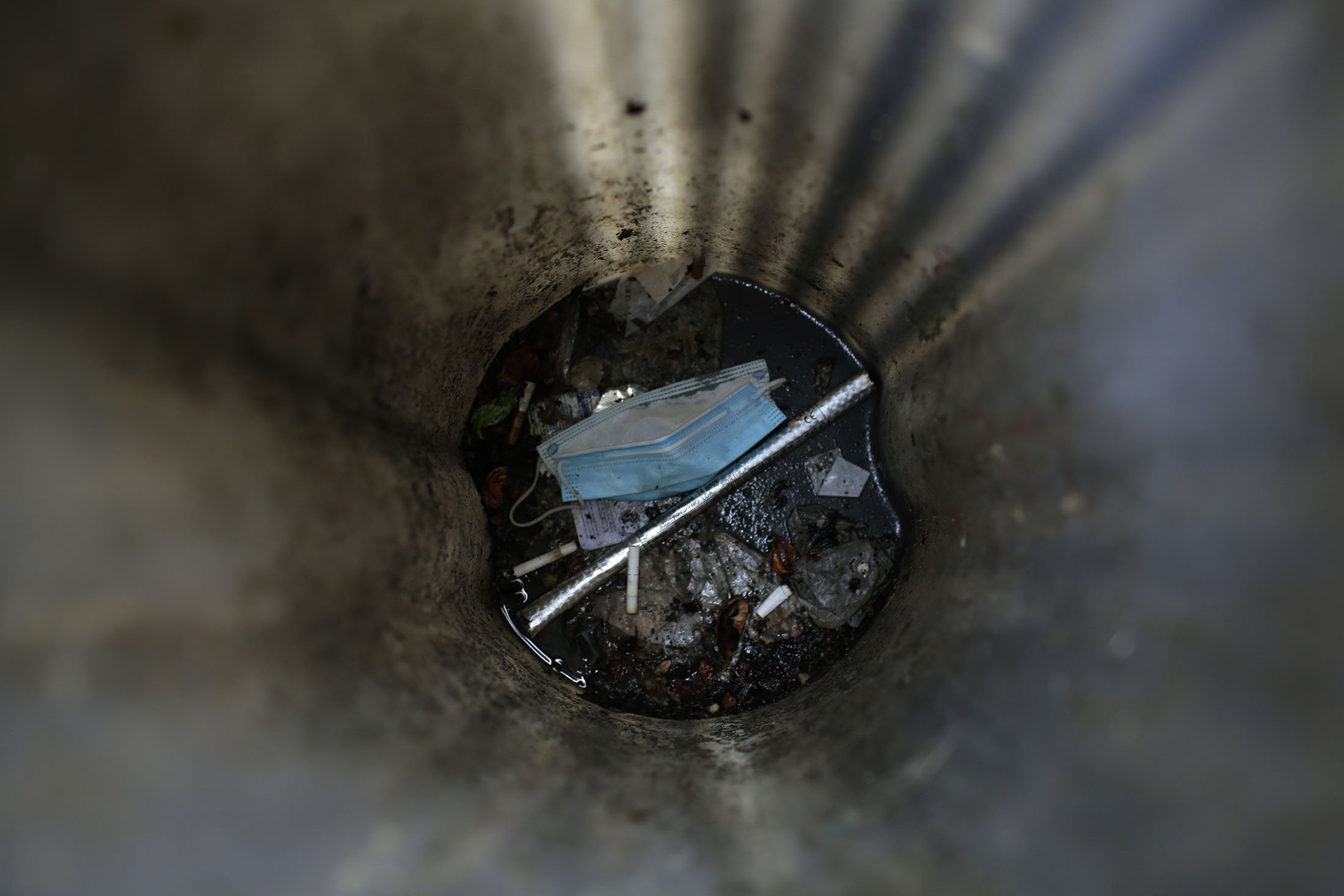 A surgical face mask rests at the bottom of a trash bin in Lisbon, Monday, Nov. 9, 2020. (AP Photo)