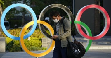 A pedestrian walks past an Olympic Rings monument displayed near the National Stadium, the main venue of the Tokyo 2020 Olympics and Paralympics, Tokyo, Japan, April 23, 2021. (EPA Photo)