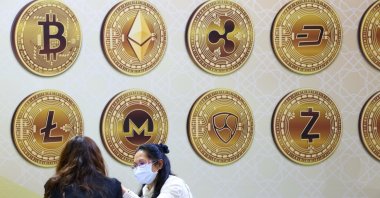 Customers talk against a backboard with signs of cryptocurrency during 2020 Taipei International Finance Expo in Taipei, Taiwan, Nov. 27, 2020. (REUTERS/Ann Wang/File Photo)