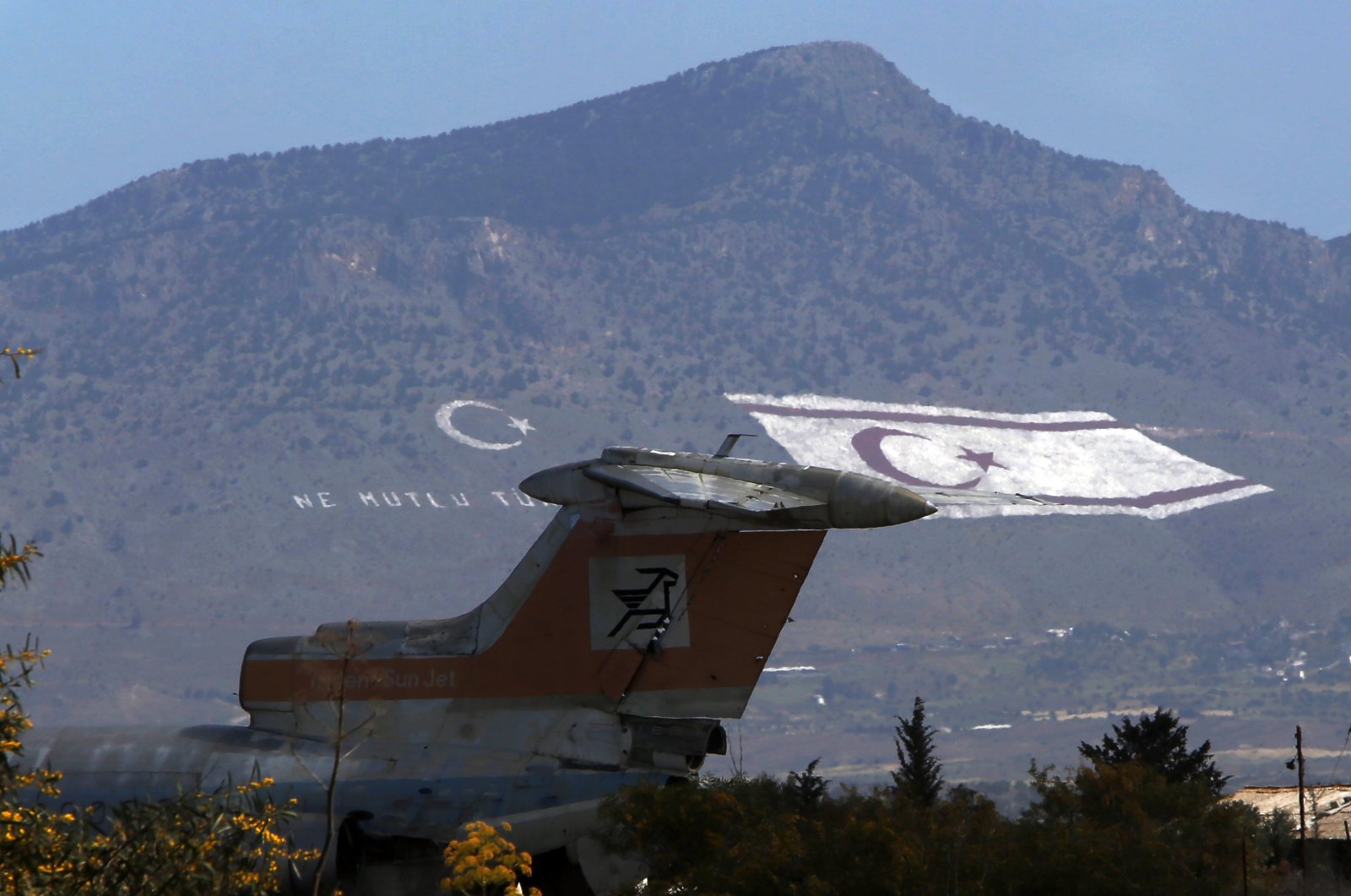 An abandoned Cyprus Airways Trident passenger jet is parked on the tarmac of the long-abandoned Nicosia airport that lies inside a United Nations-controlled buffer zone, that separates the Turkish Republic of Northern Cyprus from the Greek Cypriot administration, with a giant Turkish Cypriot, right, and Turkish flags painted on the Beşparmak Mountains in the background, on Friday, April 4, 2021. (AP Photo)