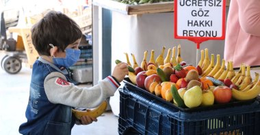 A child picks a piece of fruit from a stand offering free produce, in Afyon, western Turkey, April 29, 2021. (DHA PHOTO)