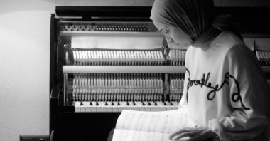 Büşra Kayıkçı poses with a music notebook in front of her piano. (Courtesy of Büşra Kayıkçı) 