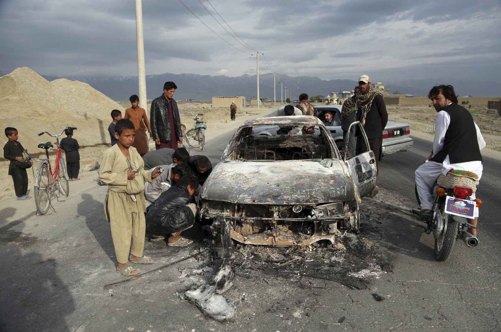 Afghans look at a civilian vehicle burnt after being shot by U.S. forces after an attack near the Bagram Air Base, north of Kabul, Afghanistan, April 9, 2019. (AP Photo)
