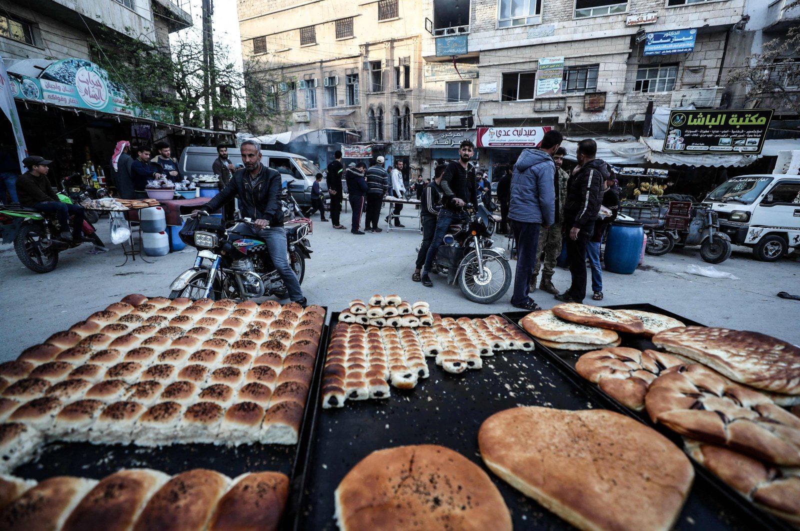 A street vendor displays pastries and bread, as Syrians buy food products at a market ahead of iftar, the evening meal that ends the daily fast at sunset, on the second day of the Islamic holy month of Ramadan, near the strategic M4 highway in the city of Ariha, in the southern countryside of Idlib province, Syria, April 15, 2021. (AFP Photo)