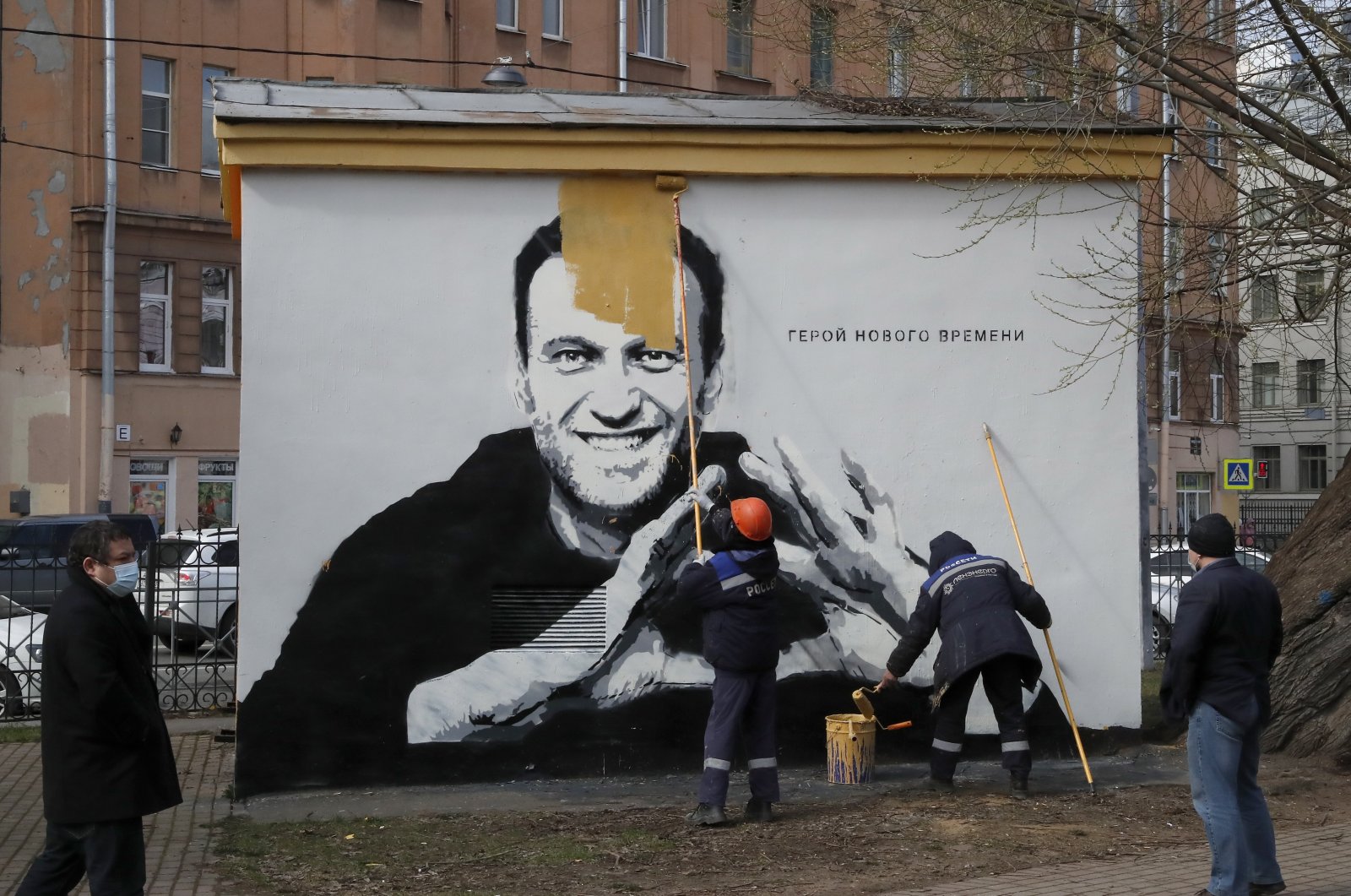 Municipal workers paint over graffiti depicting jailed Russian opposition politician Alexei Navalny that reads, "The hero of the new age," in St. Petersburg, Russia, April 28, 2021. (EPA Photo)