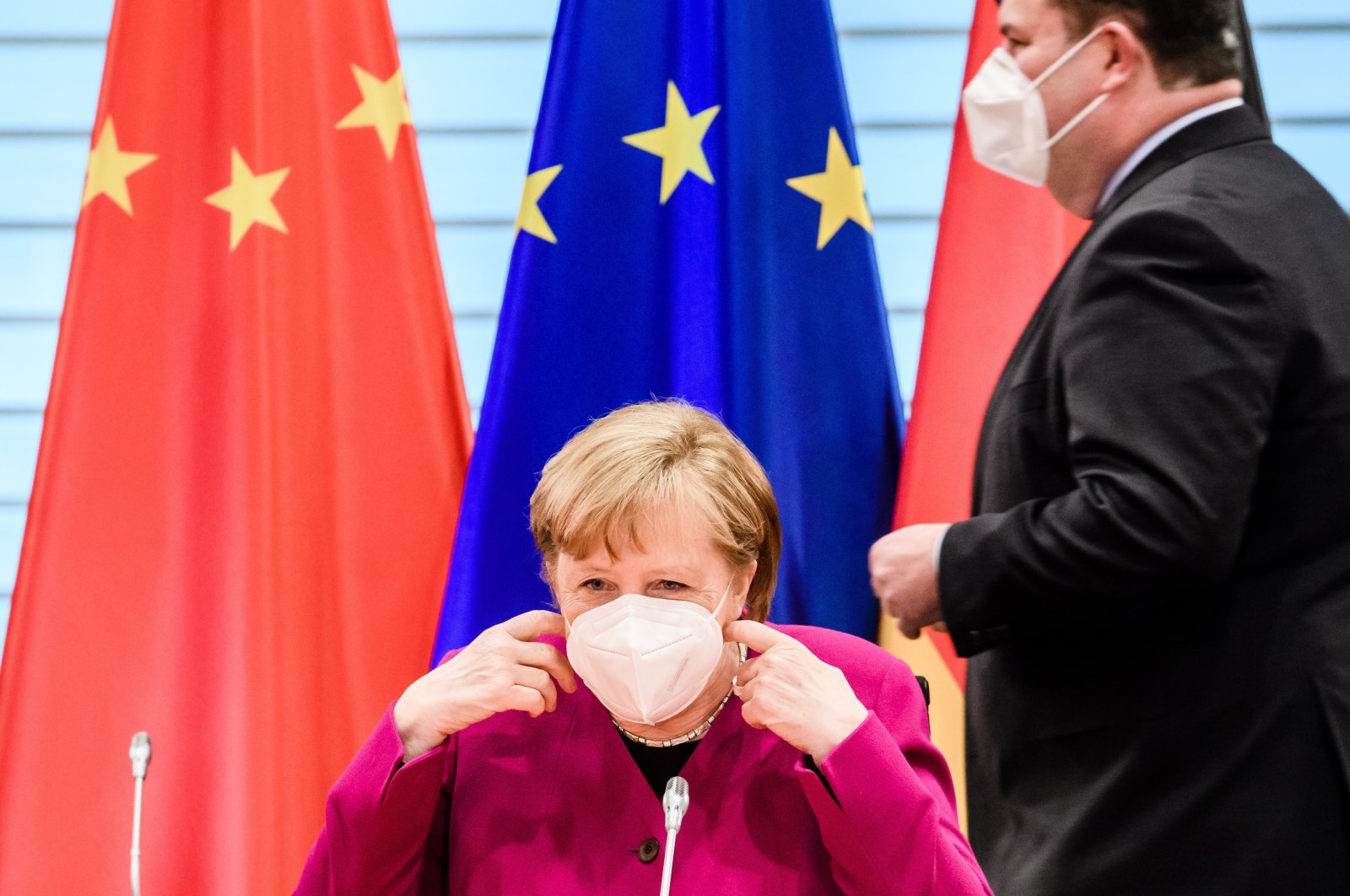 German Chancellor Angela Merkel takes off her face mask as German Minister of Labor and Social Affairs Hubertus Heil (R) passes by during the beginning of a virtual plenary session of the 6th German-Chinese government consultations in Berlin, Germany, April 28, 2021. (EPA Photo)
