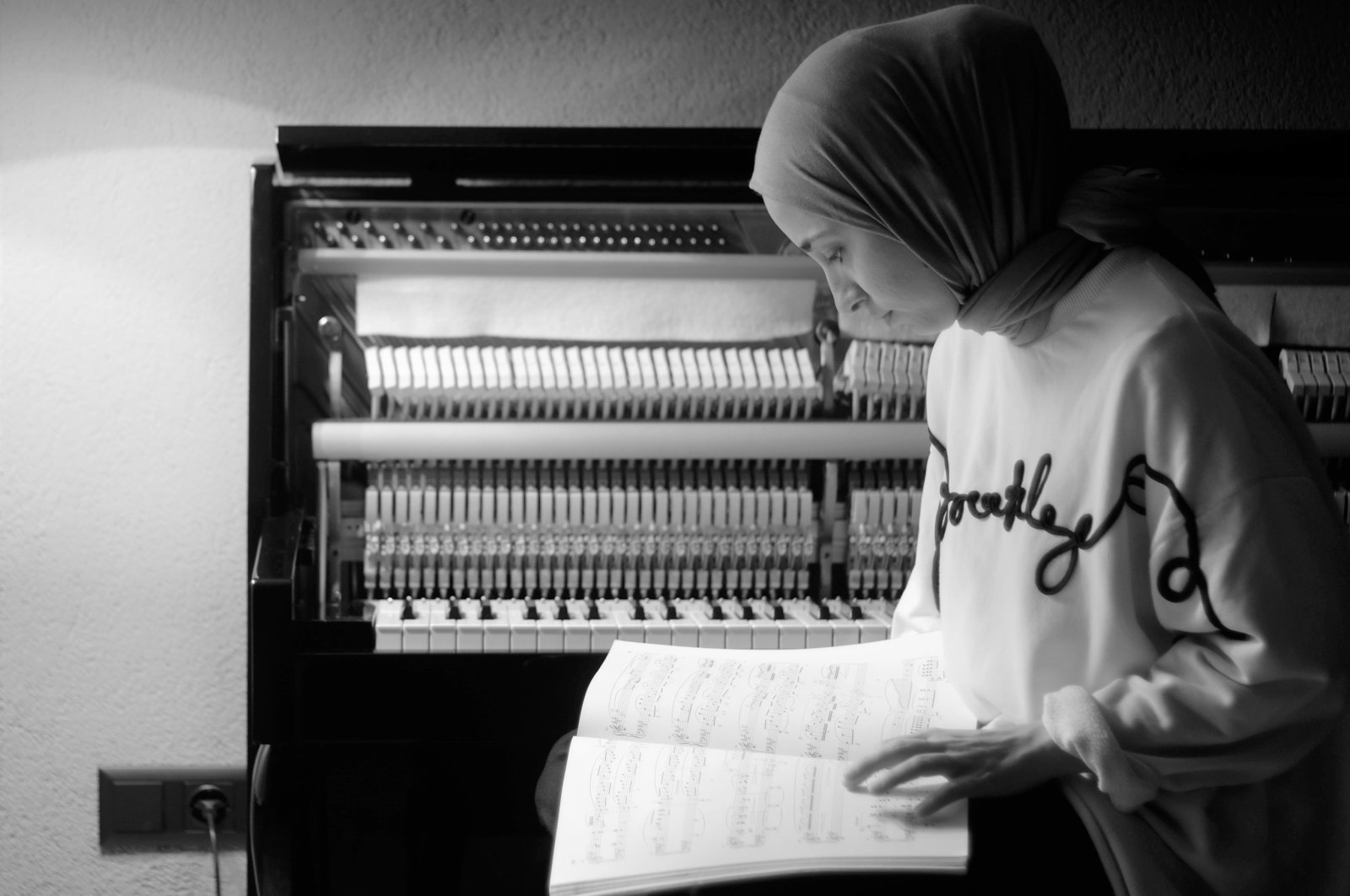 Büşra Kayıkçı poses with a music notebook in front of her piano. (Courtesy of Büşra Kayıkçı) 