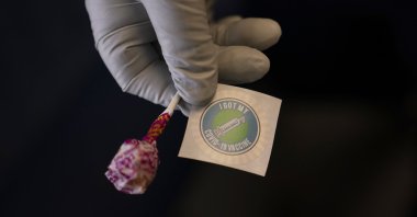 A nurse prepares a lollipop and an "I Got My COVID-19 Vaccine" sticker for a recipient in a mobile clinic set up in the parking lot of a shopping center in Orange, California, U.S., April 29, 2021.  (AP Photo)
