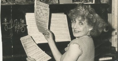 Aliye Berger poses with pages of a music notebook in front of her piano. (Courtesy of SALT Research)