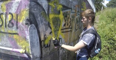 This grab taken from a video provided by the Metropolitan Police shows Benjamin Hannam spray painting graffiti which was shown to the jury during his trial at the Old Bailey in London, the U.K., Thursday, April 1, 2021. (Metropolitan Police via AP)