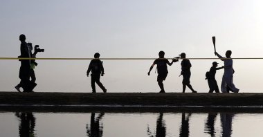 A Tokyo 2020 Olympic torch relay participant runs on a beach in Mitoyo in Kagawa Prefecture, western Japan, April 18, 2021. (Kyodo via Reuters)