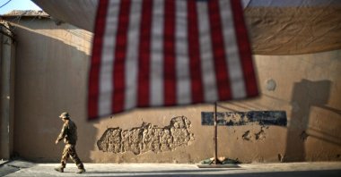 A U.S. Army soldier walks past an American Flag hanging in preparation for a ceremony commemorating the 10th anniversary of the 9/11 attacks, at Forward Operating Base Bostick in Kunar province, Afghanistan, Sept. 11, 2011. (AP Photo)