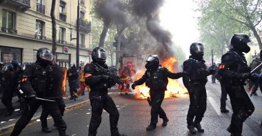 Police officers of the brigade of repression of violent action (BRAV) walk near a fire burning in the street during the annual May Day (Labor Day) rally in Paris, France, May 1, 2021. (AFP Photo)