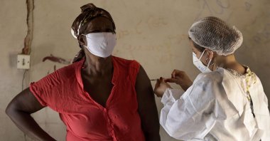 A 75-year-old woman is inoculated with the Sinovac COVID-19 vaccine during a house-to-house vaccination campaign in the Kalunga Vao de Almas quilombo on the outskirts of Cavalcante, Goias state, Brazil, March 16, 2021. (AP Photo)