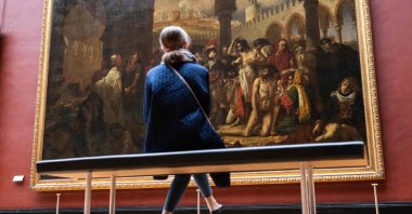A woman views the original 1804 painting of "Bonaparte visiting the plague stricken in Jaffa" by French painter Antoine-Jean Gros, on display at the Louvre museum in Paris, France, April 29, 2021. (AFP Photo)