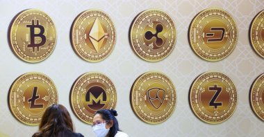 Customers talk against a backboard with cryptocurrency signs during the 2020 Taipei International Finance Expo in Taipei, Taiwan, Nov. 27, 2020. (Reuters Photo)