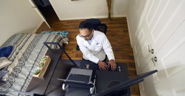 The medical director of Doctor on Demand, Dr. Vibin Roy, types notes as he listens to a patient during an online primary care visit from his home, Texas, the U.S., April 23, 2021. (AP Photo)