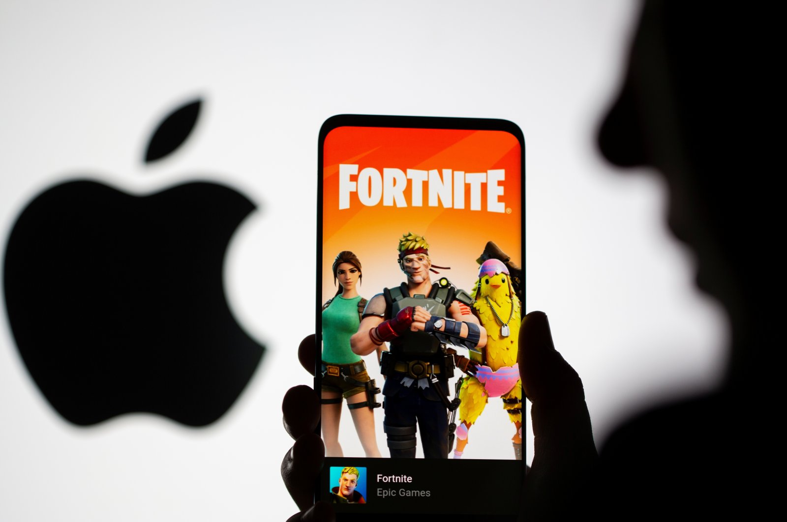 Fortnite game graphic is displayed on a smartphone in front of Apple logo in this illustration taken May 2, 2021. (Reuters Photo)