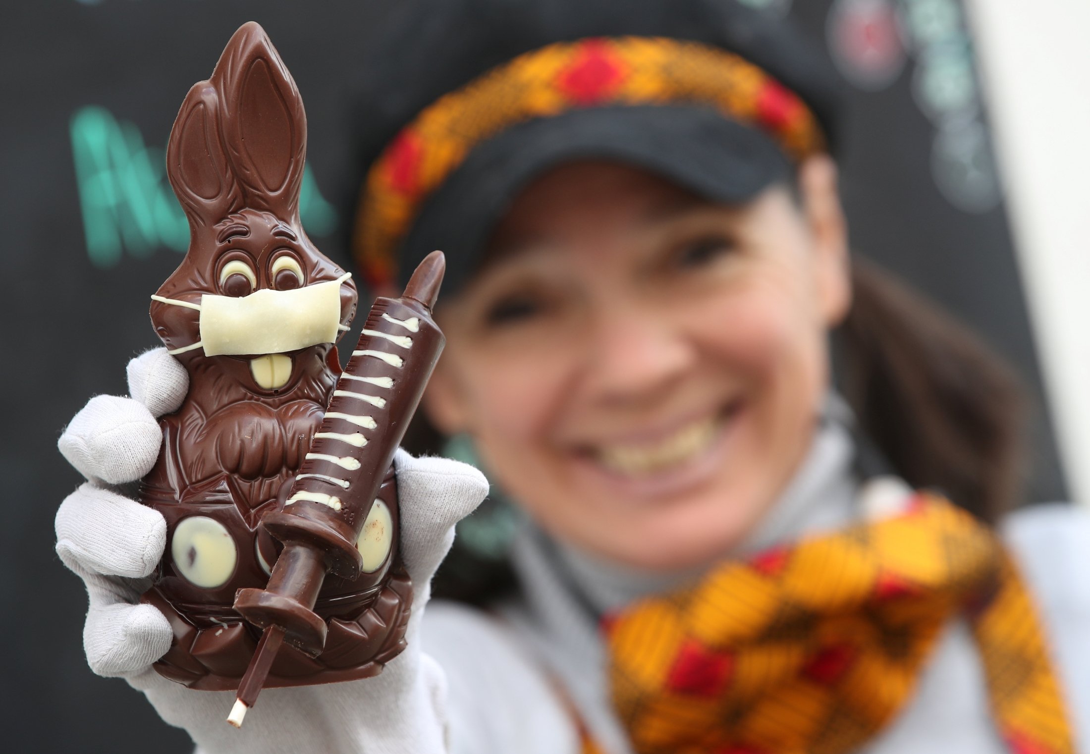 Belgian artisan chocolate maker Genevieve Trepant shows a chocolate bunny wearing a protective mask and holding a vaccine syringe called 'L'Atch'a Azteka' at her workshop, Cocoatree in Lonzee, Belgium, April 30, 2021. (Reuters Photo)