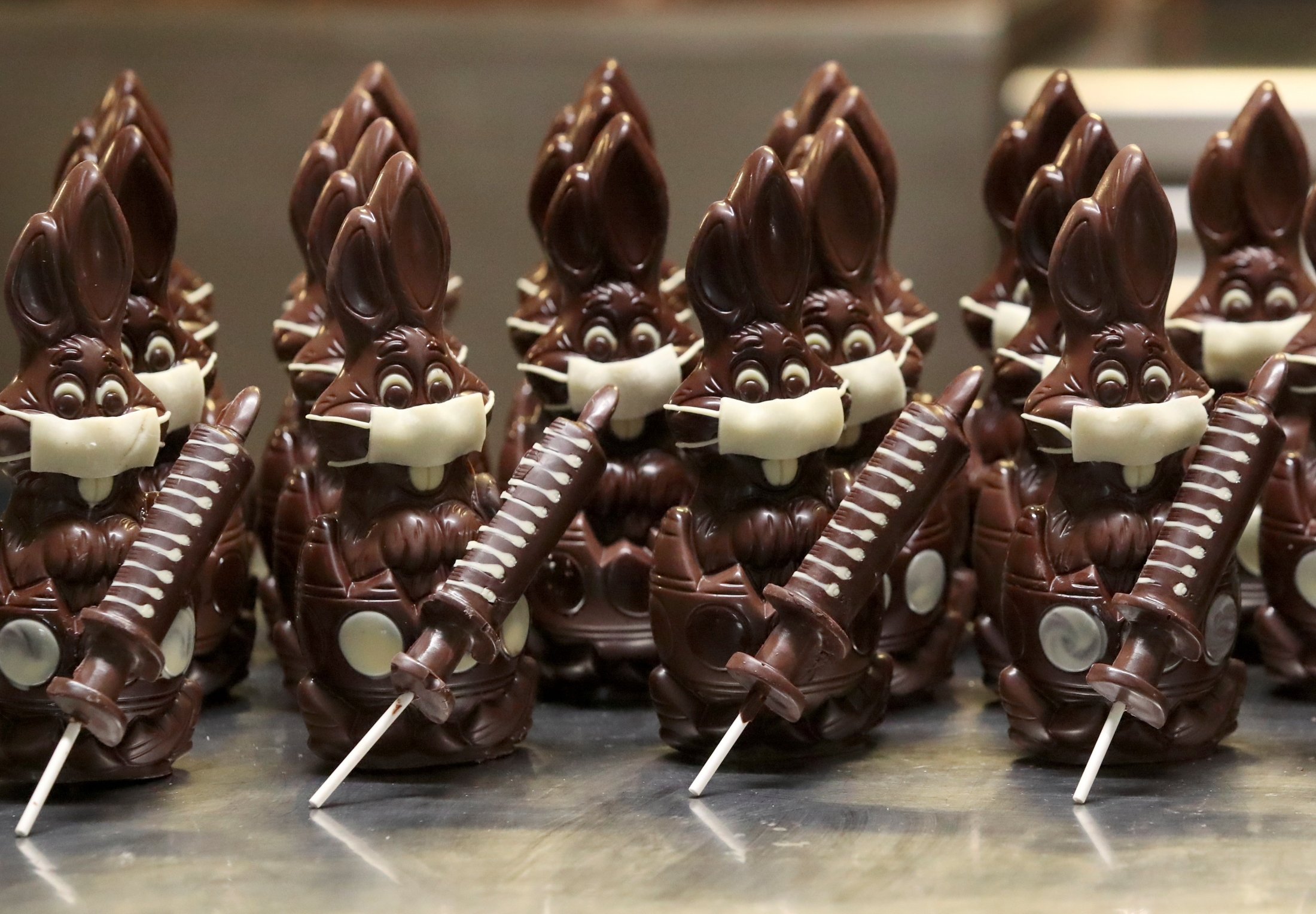 Chocolate bunnies wearing protective masks and holding vaccine syringes called “L'Atch'a Azteka” are seen at artisan Genevieve Trepant's workshop, Cocoatree in Lonzee, Belgium, April 30, 2021. (Reuters Photo)