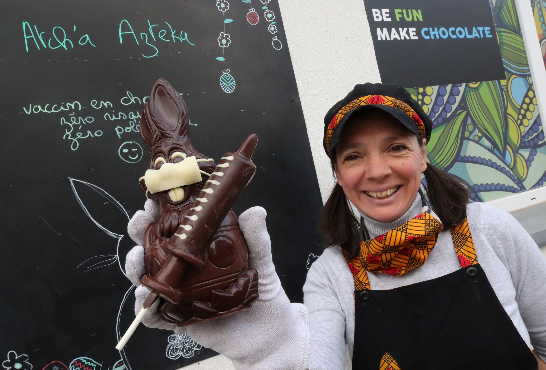 Belgian artisan chocolate maker Genevieve Trepant shows a chocolate bunny wearing a protective mask and holding a vaccine syringe called "L