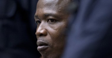 Dominic Ongwen, a senior commander in the Lord's Resistance Army, whose fugitive leader Kony is one of the world's most-wanted war crimes suspects, is flanked by two security guards as he sits in the courtroom of the International Court in The Hague, Netherlands, Dec. 6, 2016. (AP Photo)