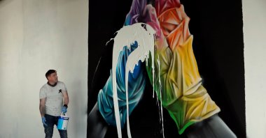 Street artist Nathan Murdoch looks at the artwork with paint splattered over it, as he creates a piece of crypto art to be auctioned with proceeds donated to the NHS in Peterborough, Britain, April 15, 2021. (Reuters Photo)