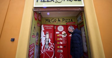 Claudio Zampiga waits for his order at the first automatic pizza vending machine, which is capable of kneading, seasoning and cooking the pizza in three minutes, in Rome, Italy, May 6, 2021. (Reuters Photo)
