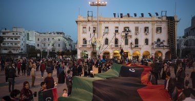 People carry a giant Libyan flag in Martyrs Square during a march commemorating the anniversary of anti-Gadhafi protests in Tripoli, Libya, Feb. 25, 2020. (AP Photo)