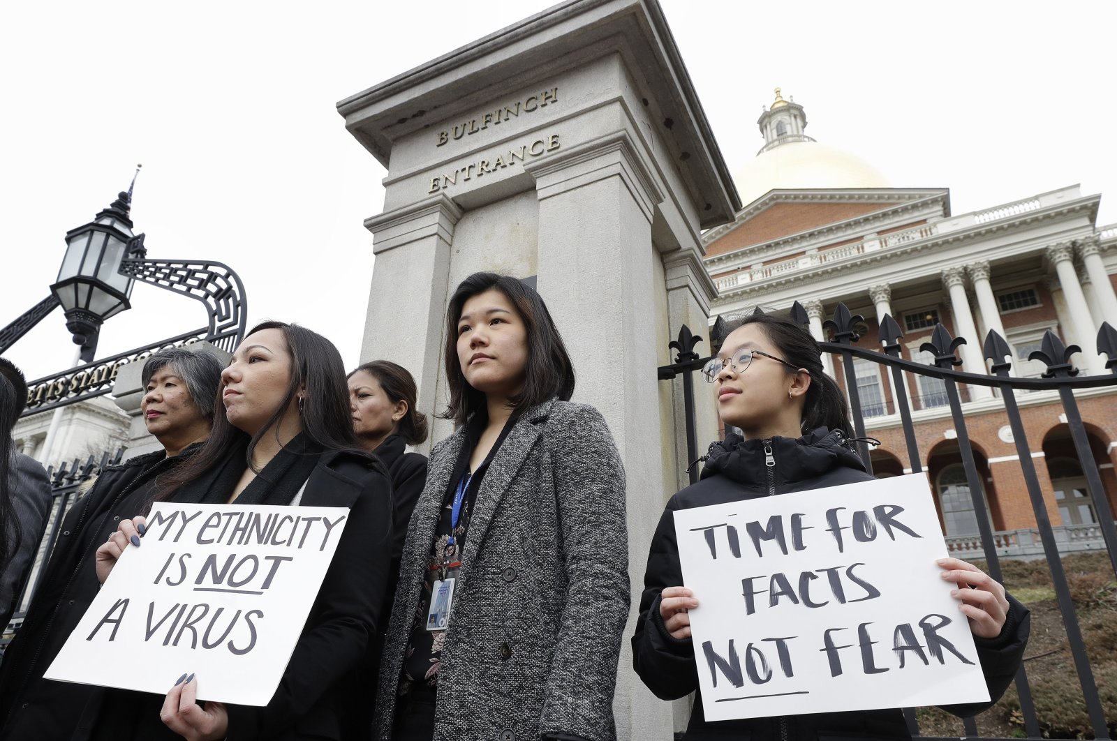 Jessica Wong (F-L) Jenny Chiang (C) and Sheila Vo, from the state's Asian American Commission, stand together during a protest on the steps of the statehouse in Boston, U.S., March 12, 2020. (AP File Photo)