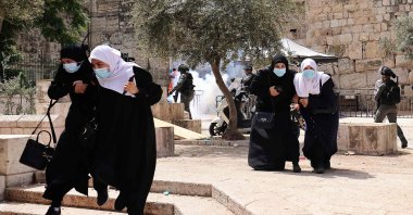 Palestinians run for cover from tear gas fired by Israeli security forces in Jerusalem's Old City on May 10, 2021. (AFP Photo)