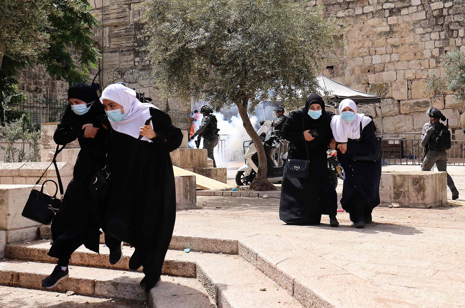 Palestinians run for cover from tear gas fired by Israeli security forces in Jerusalem's Old City on May 10, 2021. (AFP Photo)