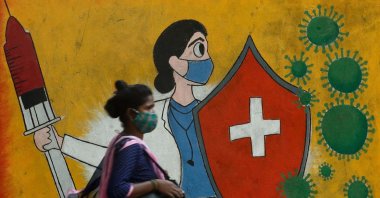 A woman walks past graffiti on a street depicting a health care worker fighting coronavirus cells, in Mumbai, India, May 10, 2021. (Reuters Photo)