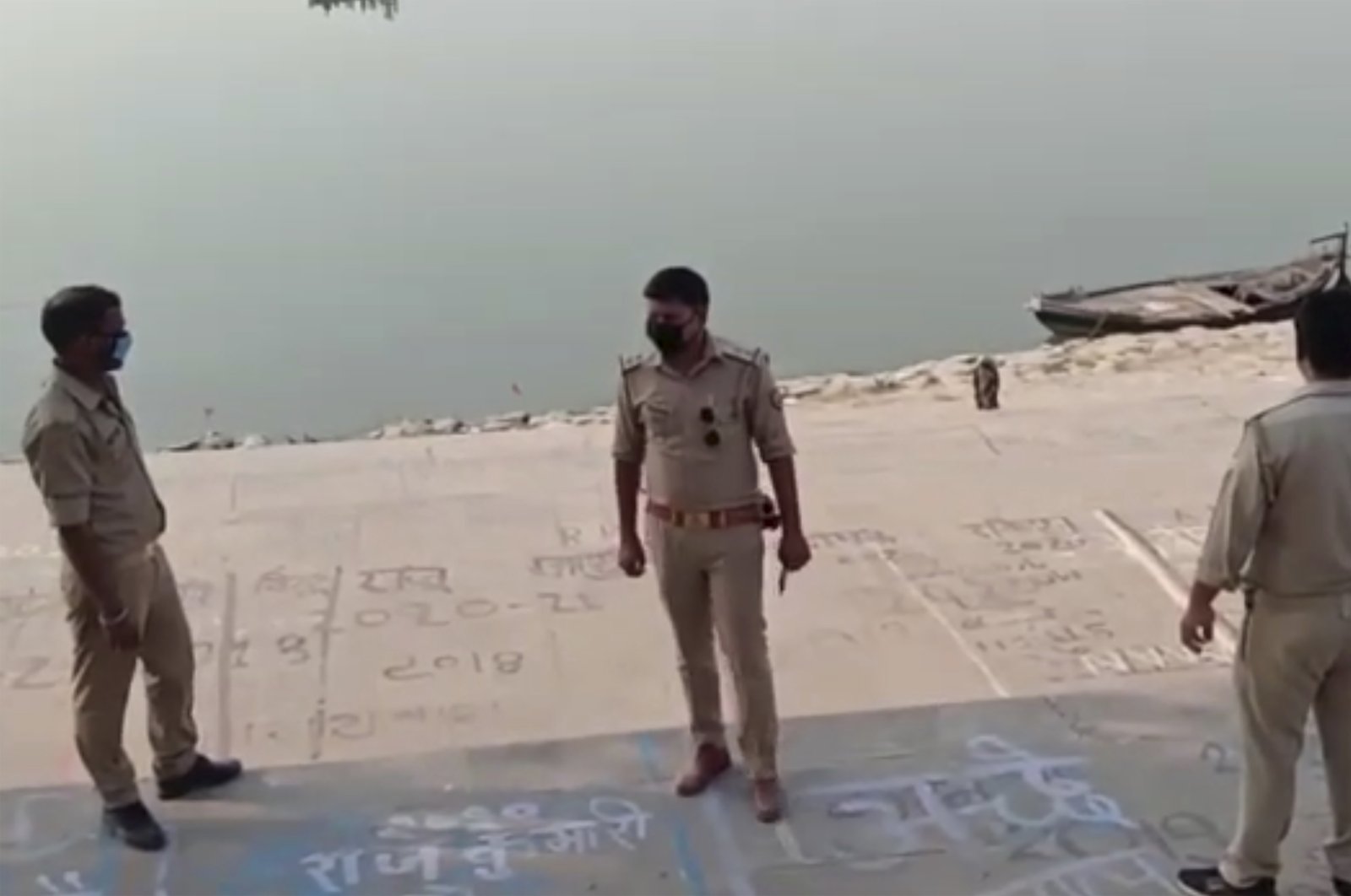 This frame grab from video provided by KK Productions shows police officials standing guard at the banks of the river where several bodies were found lying in Ghazipur district in Uttar Pradesh state India, Tuesday, May 11, 2021. (AP Photo)