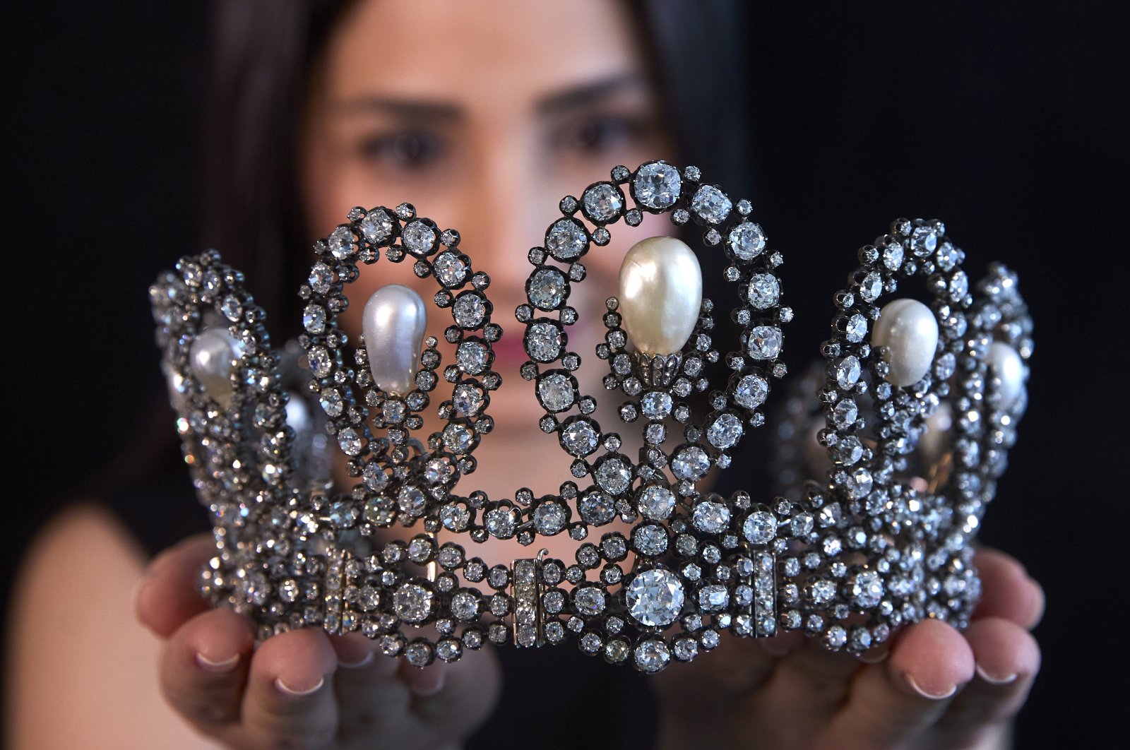 A staff holds a diamond and pearl tiara passed down through generations of the Italian royal family during a preview at Sotheby's before their auction in Geneva, Switzerland, May 6, 2021.  (Reuters Photo)