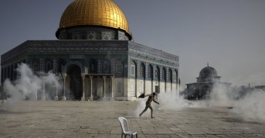 A Palestinian man runs away as Israeli police fire tear gas at the Al-Aqsa Mosque compound, East Jerusalem, occupied Palestine, May 10, 2021. (AP Photo)