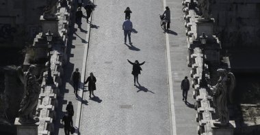 People stroll along the Sant'Angelo Bridge in Rome, Tuesday, March 2, 2021. (AP Photo)