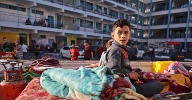 A Palestinian boy who fled his home due to Israeli air and artillery strikes sits on a mattress outside a school hosting refugees in Gaza City, Palestine, May 14, 2021. (AFP Photo)