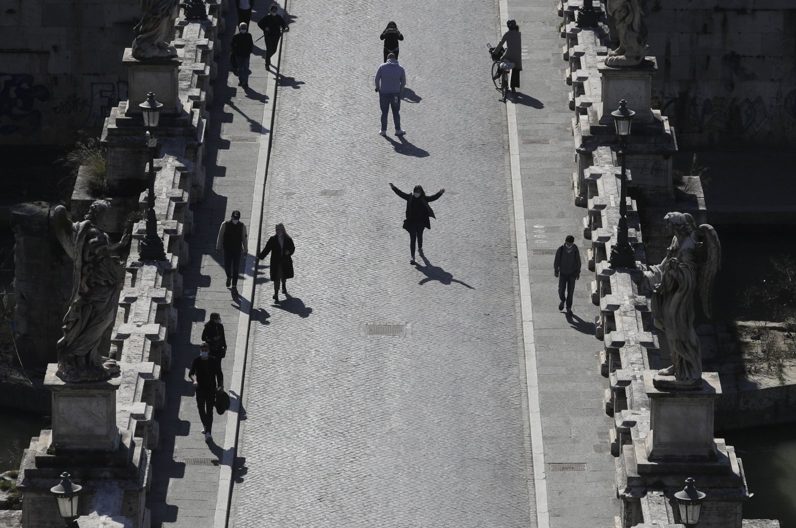 People stroll along the Sant'Angelo Bridge in Rome, Tuesday, March 2, 2021. (AP Photo)