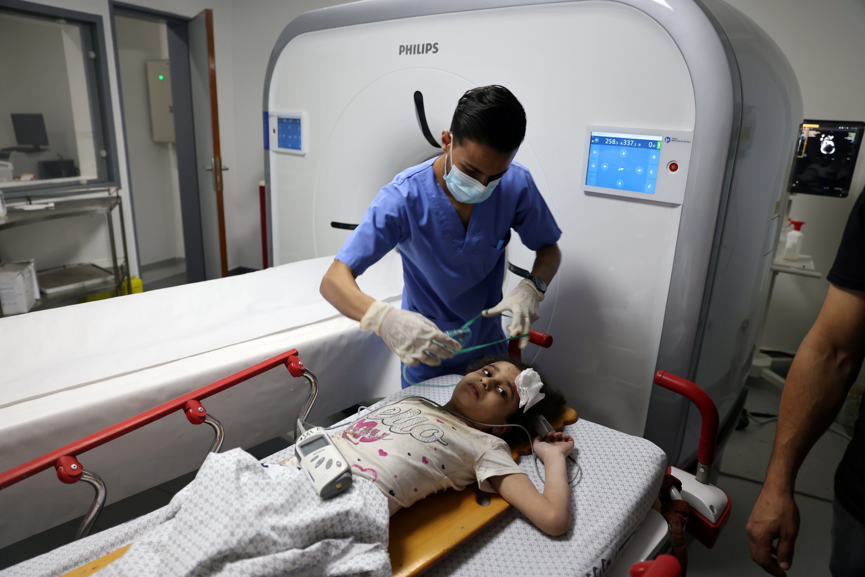 Palestinian girl Suzy Eshkuntana, 6, is treated by a medic at a hospital after being pulled from the rubble of a building amidst Israeli airstrikes, in Gaza City, May 16, 2021. (Reuters Photo)