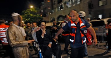 Israeli medics evacuate an injured an ultra-Orthodox Jewish man after the collapse of grandstand seating at a synagogue in the Israeli settlement of Givat Zeev in the occupied West Bank outside Jerusalem, on May 16, 2021. (AFP Photo)