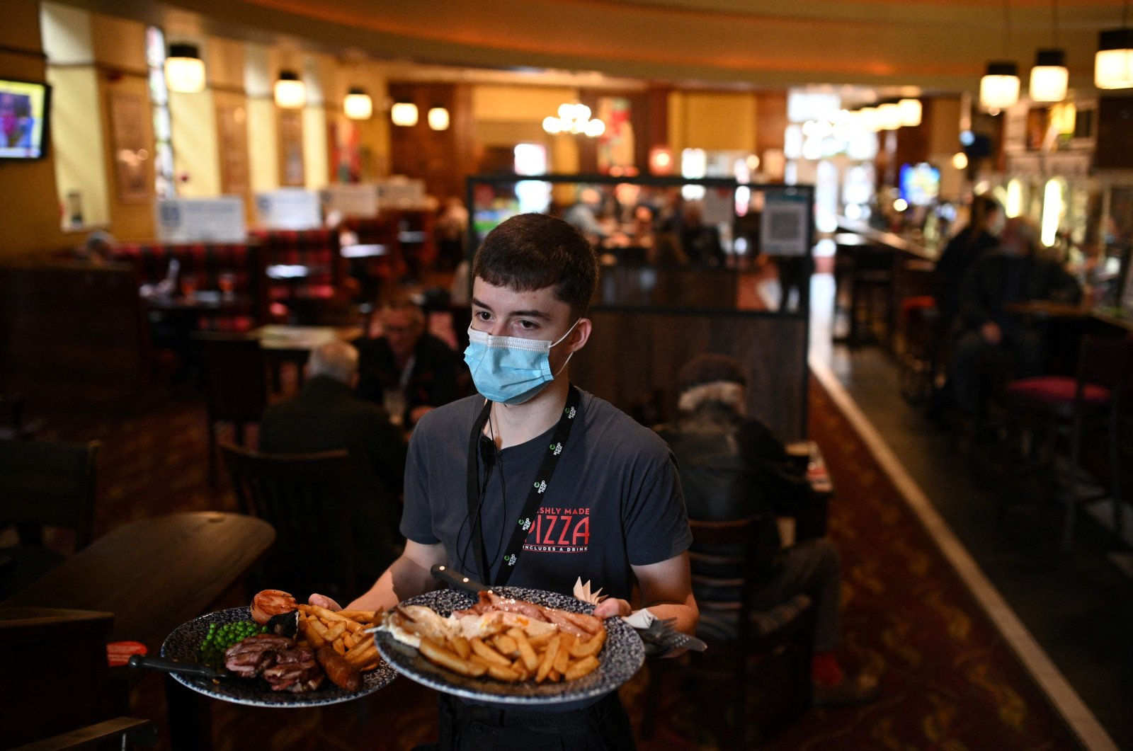 A member of the bar staff serves food in a Wetherspoons pub in Leigh, Greater Manchester, northwest England, Oct. 22, 2020. (AFP Photo)
