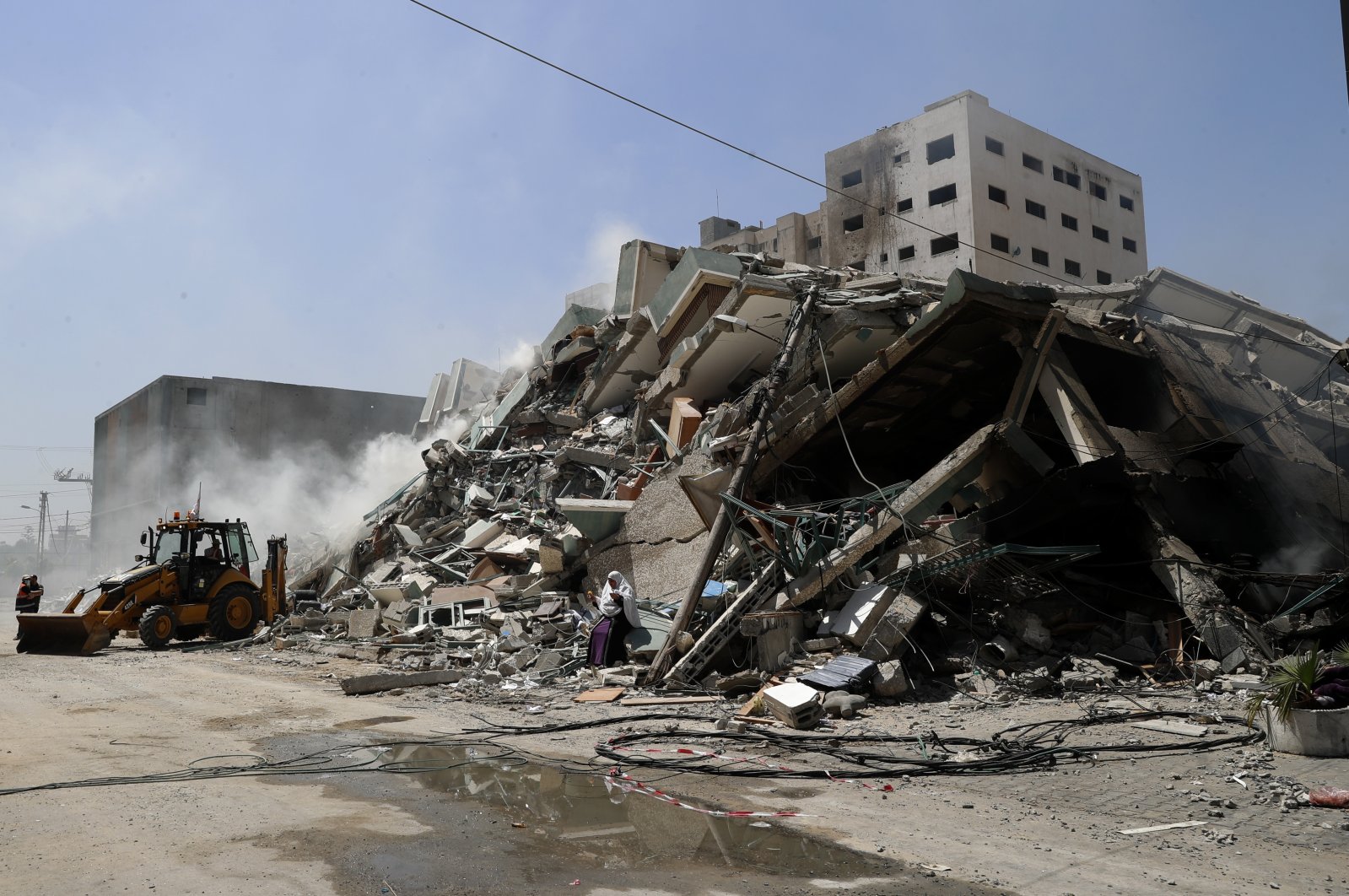 Workers clear the rubble of a building that was destroyed by an Israeli airstrike on Saturday, that housed The Associated Press, broadcaster Al-Jazeera and other media outlets, in Gaza City, May 16, 2021. (AP Photo/Adel Hana)