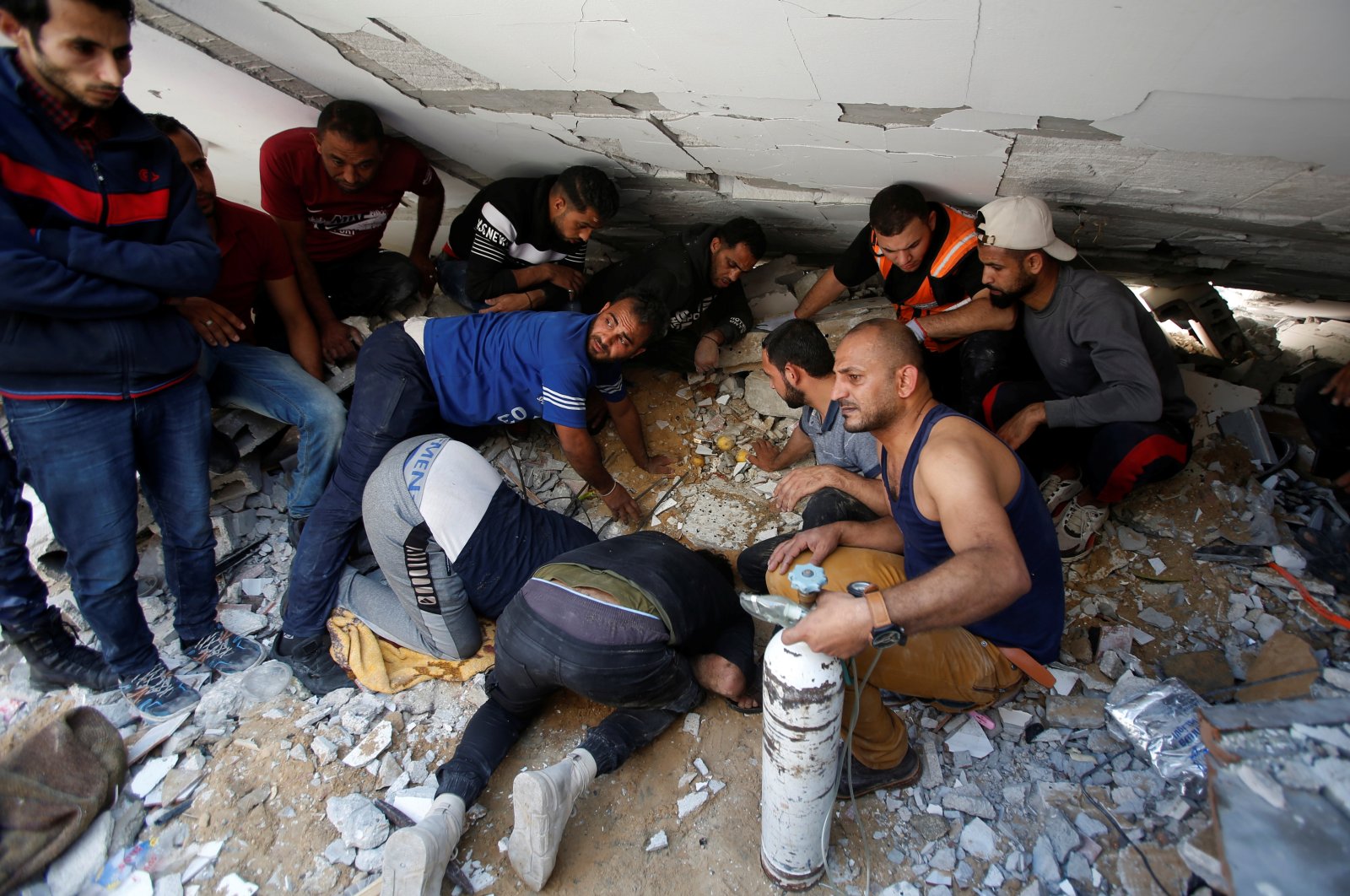 Rescuers search for people in the rubble of a building at the site of Israeli airstrikes, in Gaza City, May 16, 2021. (Reuters Photo)