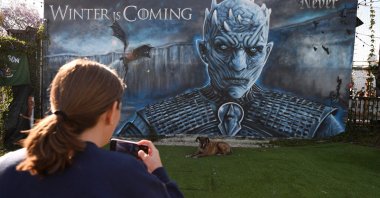 A woman takes a photo of her dog in front of a "Game of Thrones" mural outside Brennan's bar before a viewing party for HBO's "Game of Thrones" series finale in Marina del Rey, California, U.S., May 19, 2019. (AFP Photo)