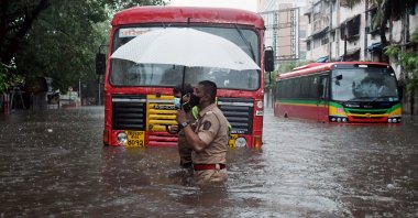 An Indian police officer helps a driver cross a street flooded by heavy rain caused by cyclone Tauktae in Mumbai, India, May 17, 2021. (EPA Photo)